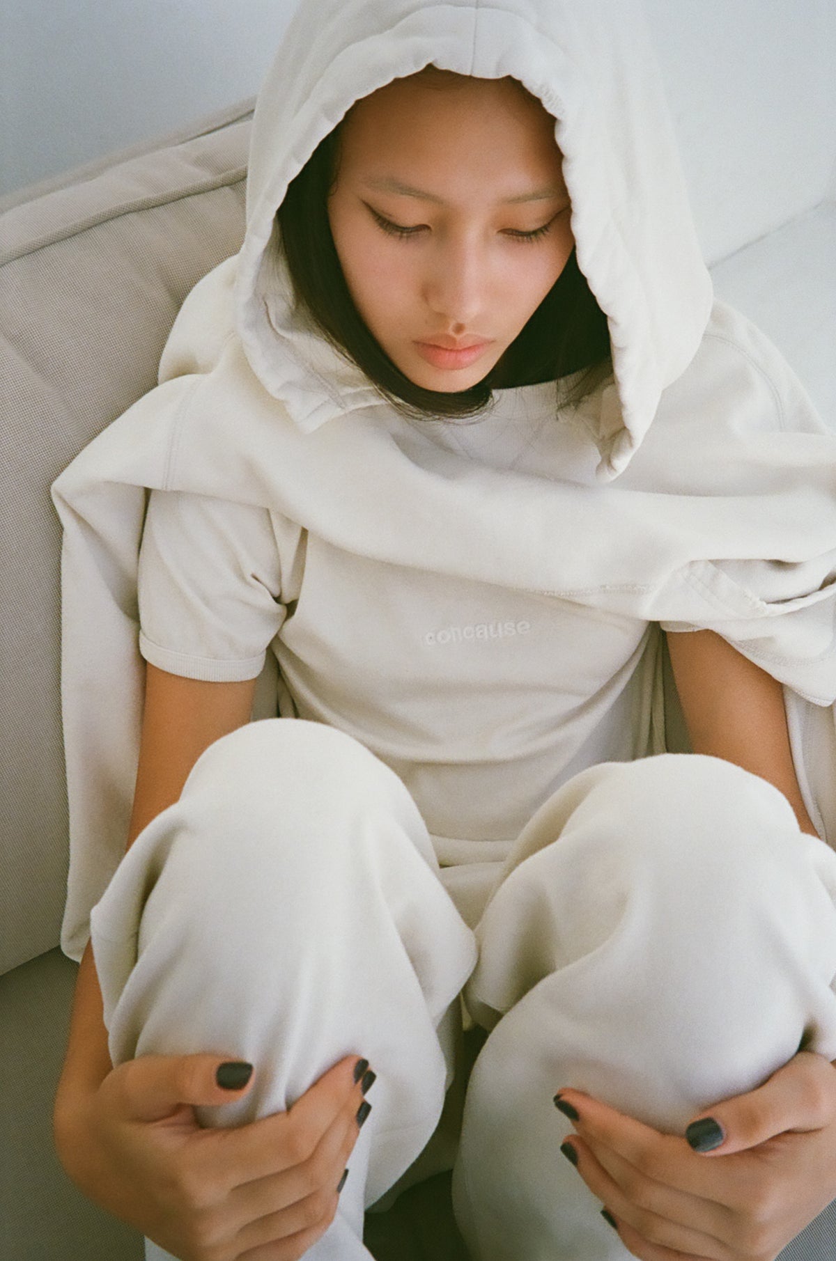 concause W-V AFTER HOODIE ルックスタイリング / OFF WHITE 女性モデル ソファ座り フードかぶり クローズアップ
